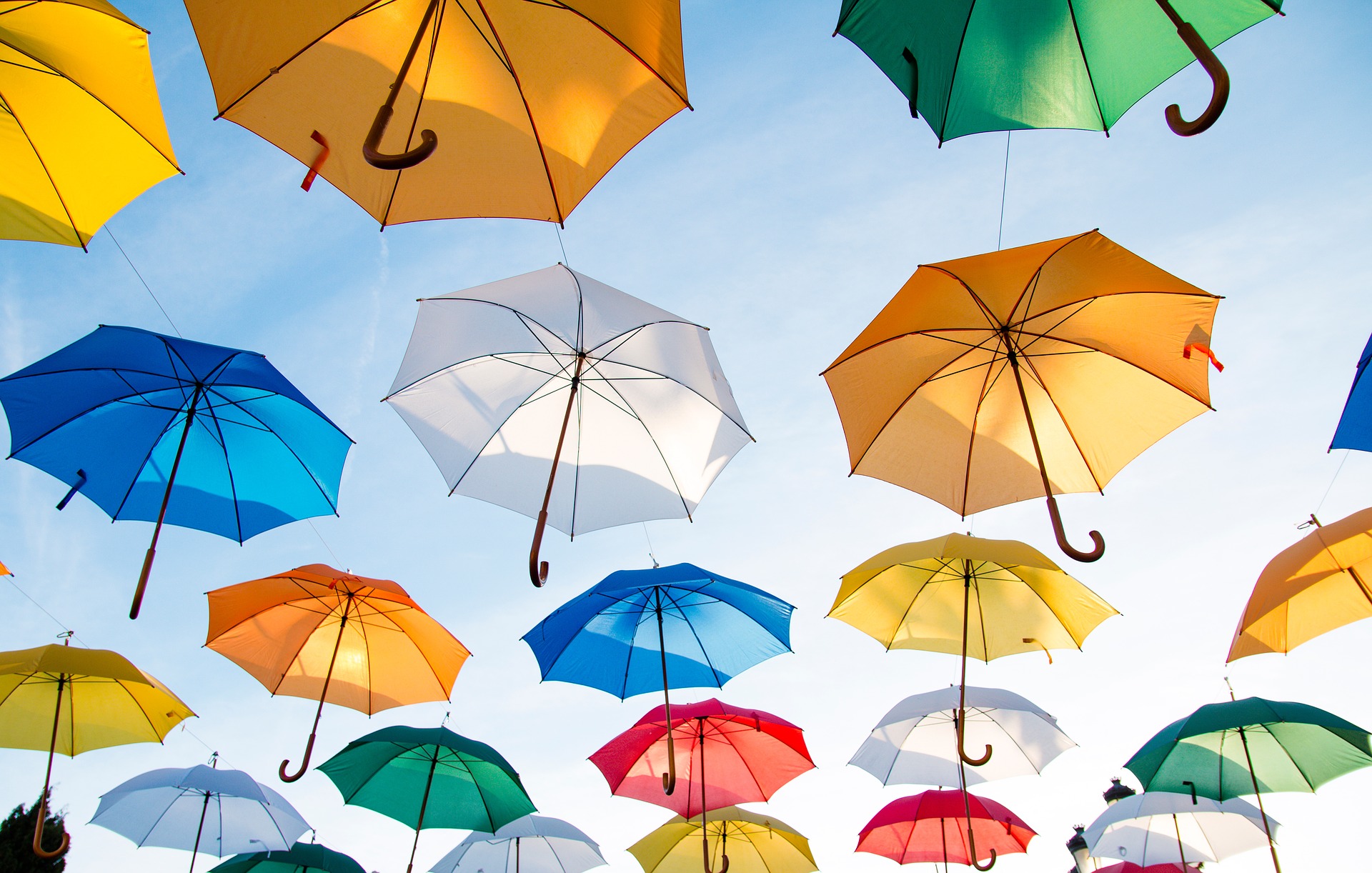 Kuvituskuva värikkäitä sateenvarjoja taivaalla