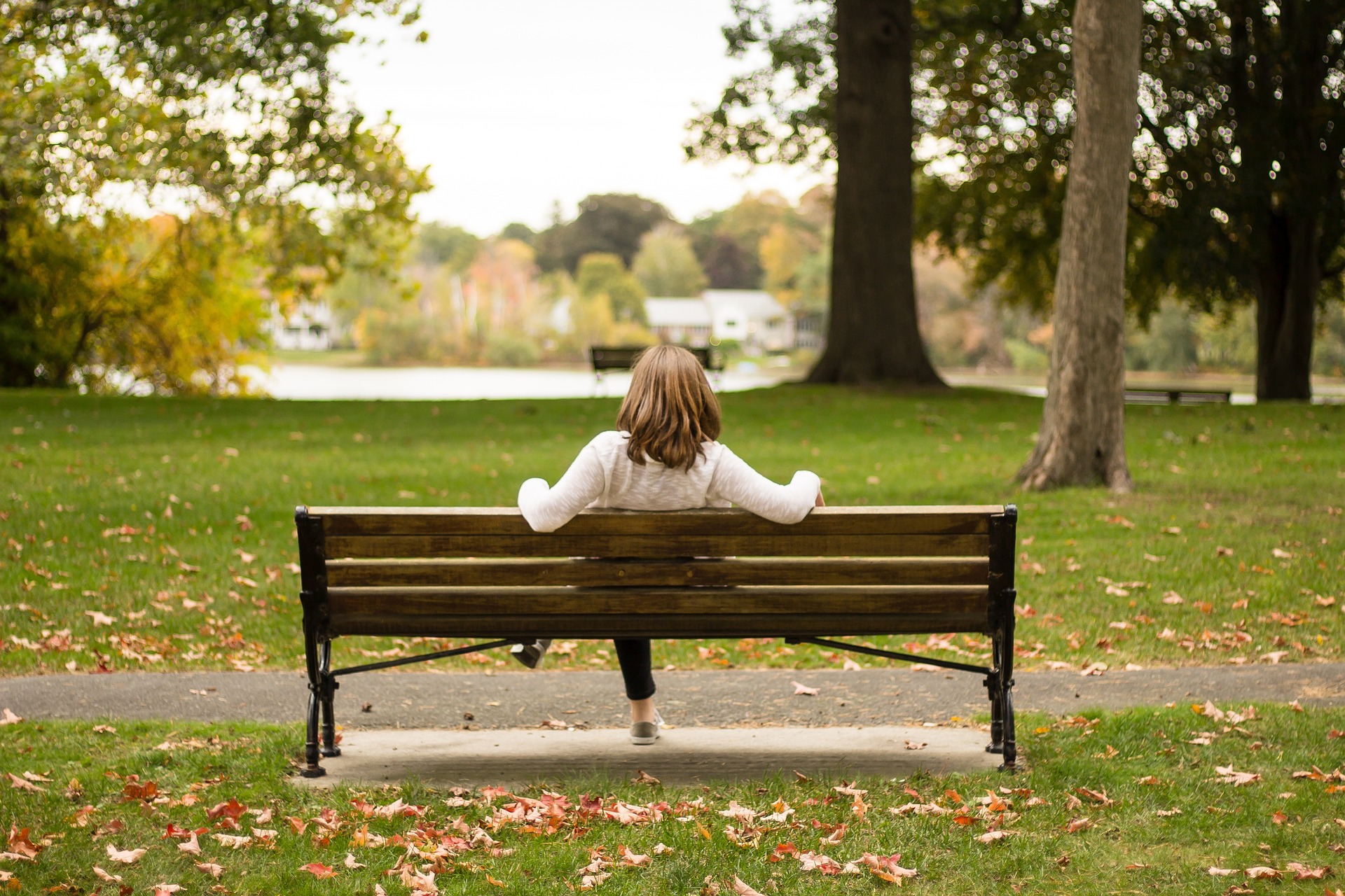 Nainen istuu puistossa yksin.