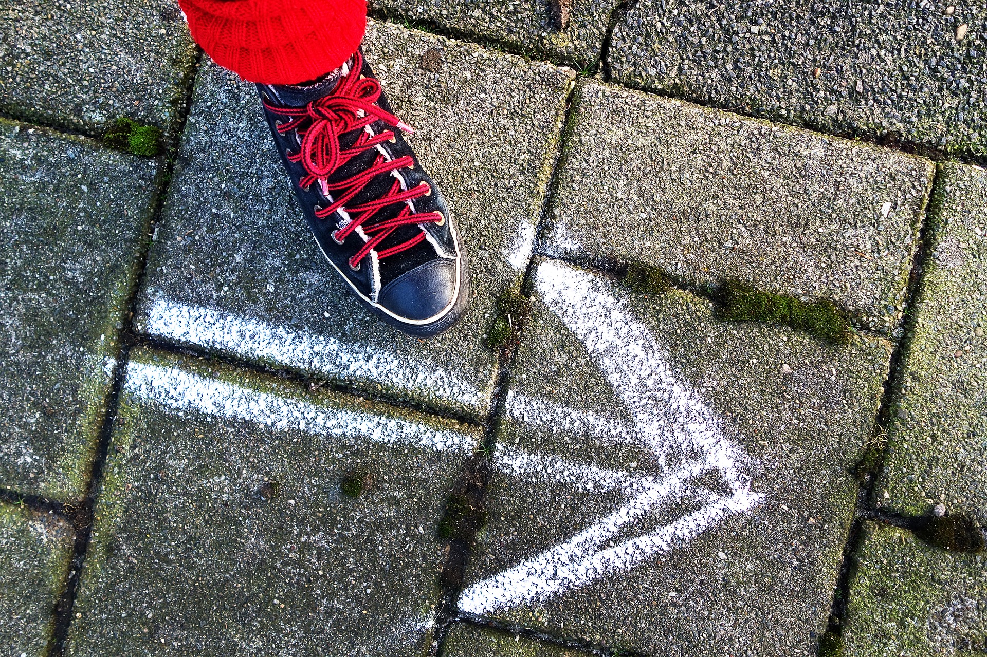 kuvituskuva: jalka ja asfalttiin maalattu nuoli.