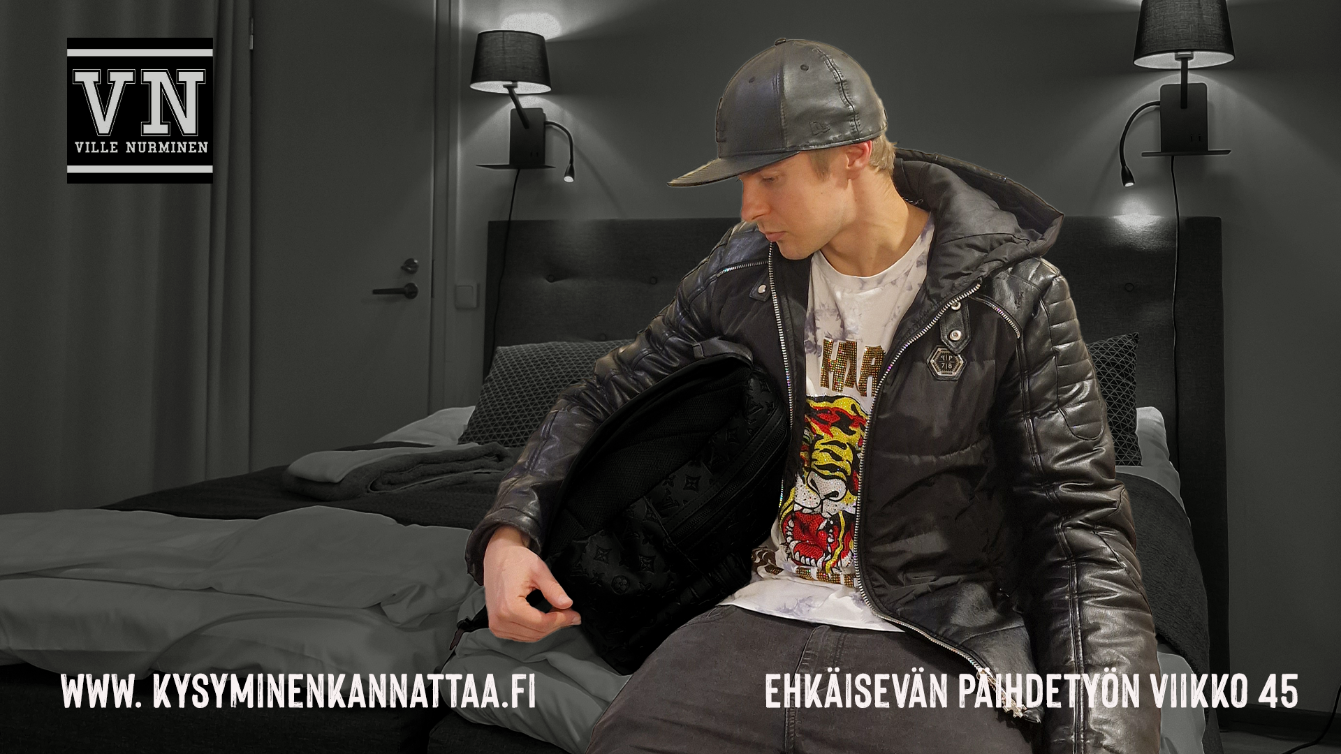 Ville Nurminen istuu hotellin sängyllä ulkovaatteet päällä, valmiina lähtemään. Tekstit: www.kysyminenkannattaa.fi Ehkäisevän päihdetyön viikko 45 ja Ville Nurmisen logo